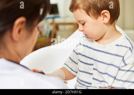 Pediatrician ties bandage around arm or wrist of child in case of sprain Stock Photo