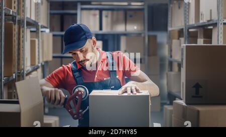 Professional Warehouse Worker Finishes Order, Sealing Cardboard Boxes Ready for Shipment. In the Background Rows of Shelves with Cardboard Boxes with Stock Photo
