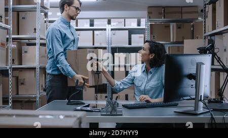 Female Inventory Manager Scans Cardboard Box and Digital Tablet with Barcode Scanner, Worker Holds Package. In the Background Rows of Cardboard Boxes Stock Photo