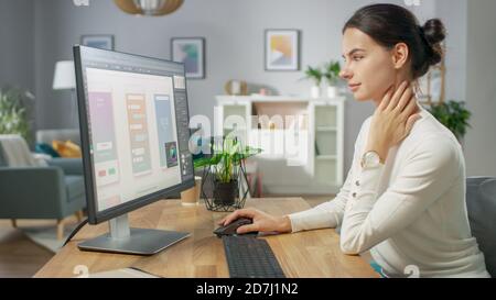 Beautiful Female Software Designer Works on a UX UI Mobile App Template, Uses Personal Computer. Freelance Programmer Working from Home. Mock-up App Stock Photo
