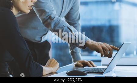 Close-up Shot of a Female Executive Listens to Her Project Manager Giving Advise, Pointing at Data Shown on a Laptop. Businesspeople Having Discussion Stock Photo