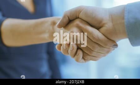 Out of Focus Businesswoman Shakes Her Hand with a Businessman. Hands in Focus. Finalizing the Deal and Concluding Contract with a Handshake. Stock Photo