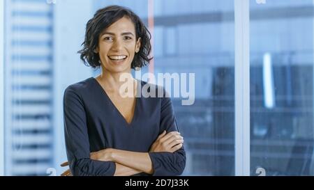 Portrait of the Successful Businesswoman Crossing Her Arms and Smiles. Beautiful Woman Executive Standing in Her Office. Stock Photo