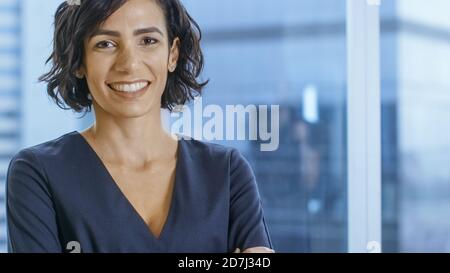 Portrait of the Successful Hispanic Businesswoman Crossing Her Arms and Smiling. Beautiful Female Executive Standing in Her Office. Stock Photo