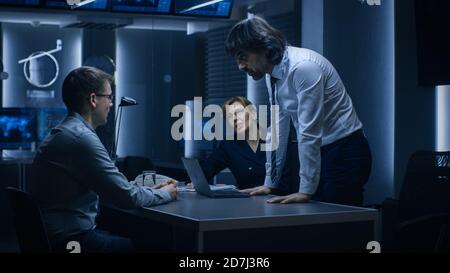 Male and Female Special Service Agents Interrogate Young Suspect in Cyber Crimes, Officer Looses Temper and Threatens Accused while Questioning. Dark Stock Photo