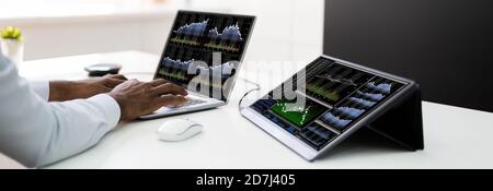 Stock Exchange Analyst Using Multiple Laptop Computer Screens Stock Photo