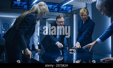Diverse Team of Government Intelligence Agents Standing Around Digital Touch Screen Table and Tracking Suspect. FBI Agents Using Satellite Stock Photo