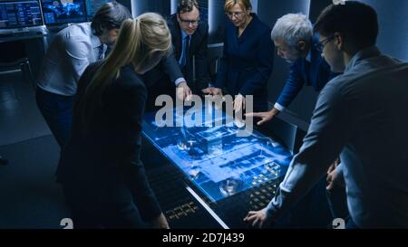 Team of Government Intelligence FBI Agents Standing Around Digital Touch Screen Table and Tracking Suspect Vehicle Using Satellite Surveillance in the Stock Photo