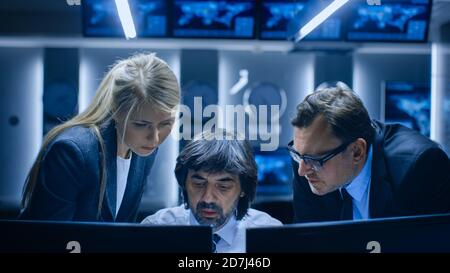Male and Female Operators Working On Computers in System Control Room. Secret Government Agency Analysts Doing Research, Conducting Cyber Security Stock Photo