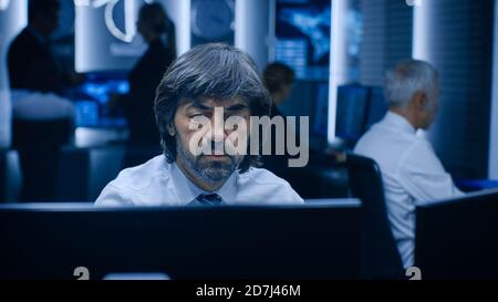 Professional Operators Working On Computers in System Control Room. Secret Government Agency Analysts Doing Research, Conducting Cyber Security Stock Photo