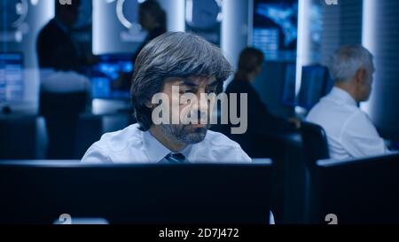 Professional Operators Working On Computers in System Control Room. Secret Government Agency Analysts Doing Research, Conducting Cyber Security Stock Photo