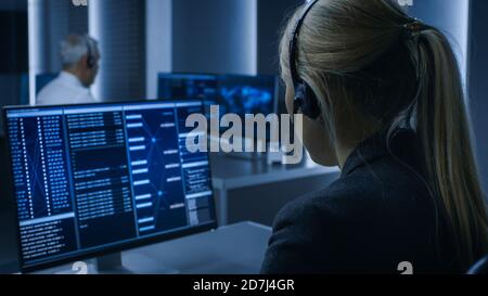 Back View of the Female Controller wearing Headset Working on Personal Computer, Monitoring Processes in the System Control Room full of Special Stock Photo