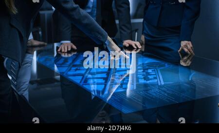 Diverse Team of Government Intelligence Agents Standing Around Digital Touch Screen Table and Satellite Tracking Suspect, Pointing at Display. Big Stock Photo