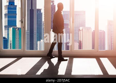 African Businessman Viewing City Downtown Through Window Stock Photo