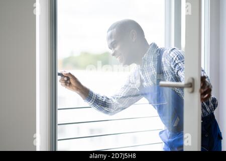 Young African Repairman In Overalls Installing Window Stock Photo