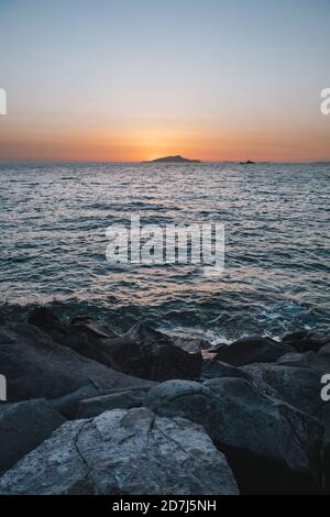 Sunset behing Ischia Island on the Sorrento Coast in Italy with Rocks and the Tyrrhenian Sea Coast Stock Photo