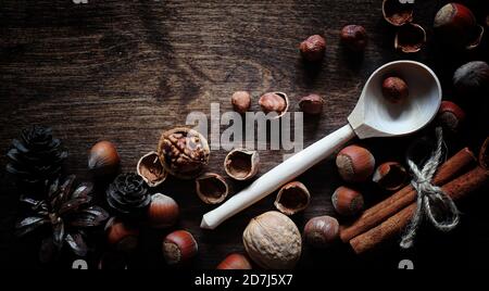 Nuts on a wooden table.Hazelnuts in the shells and shelled. A wooden spoon and nuts on a brown table. Stock Photo