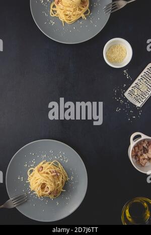 Traditional Italian dish spaghetti carbonara with bacon in a cream sauce in a plate over dark background. Top view with copy space. Stock Photo