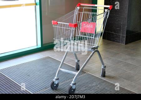Supermarket products, household goods. Cart for goods, the girl goes along the rows of the store Stock Photo