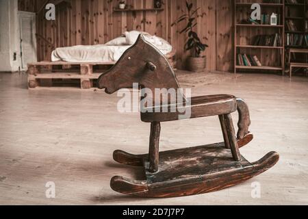 Antique wooden toy horse on the floor of spacious bedroom. Happy childhood memories concept Stock Photo