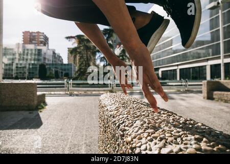 Legs of young man jumping over wall performing parkour in city Stock Photo