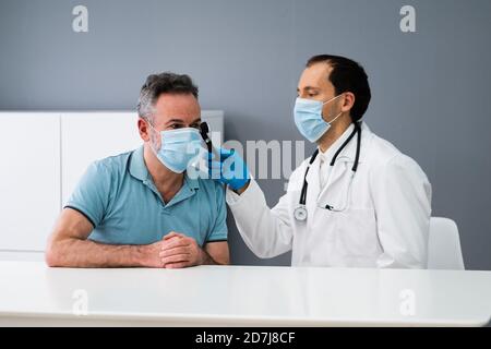 Otolaryngology Check. Doctor Checking Ear Using Otoscope In Face Mask Stock Photo
