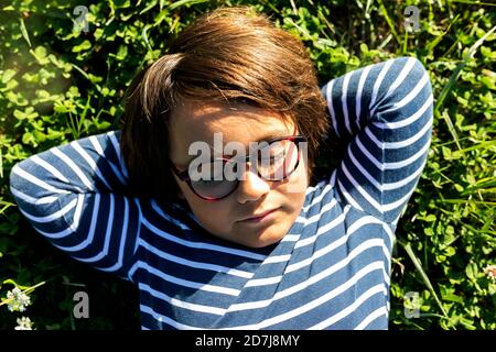 Boy with hands behind head sleeping on grass in meadow Stock Photo