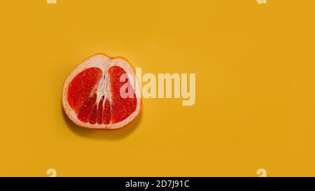 Sliced red grapefruit with copy space on bright yellow background. Stock Photo