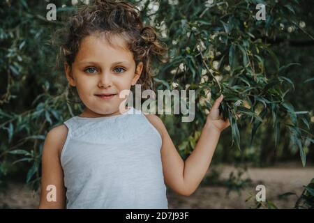 Cute little girl standing under willow tree Stock Photo