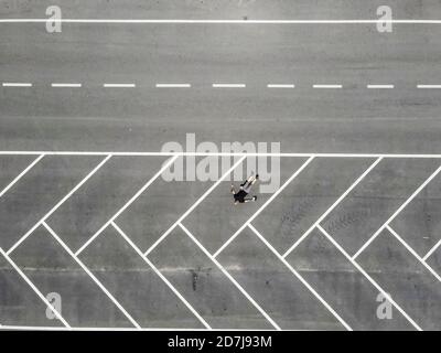 Drone view of man lying on back in empty parking lot Stock Photo
