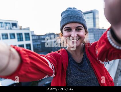 Close-up of smiling young woman standing on terrace against clear sky at sunset Stock Photo