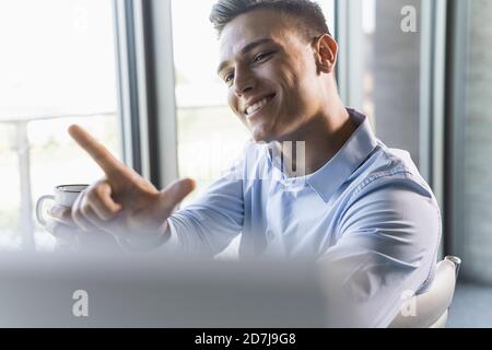 Close-up of smiling businessman gesturing while sitting in office Stock Photo