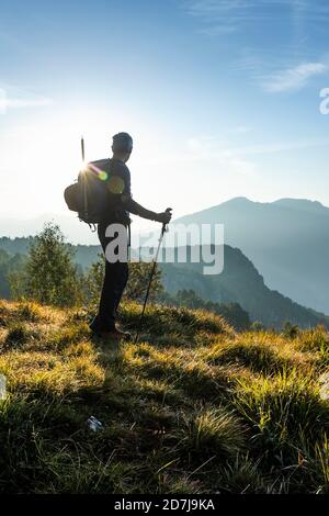 Silhouette male hiker looking at view while standing on mountain during sunrise, Orobie, Lecco, Italy Stock Photo