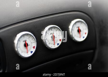 Close up shot of three white gauges in a black car dashboard Stock Photo