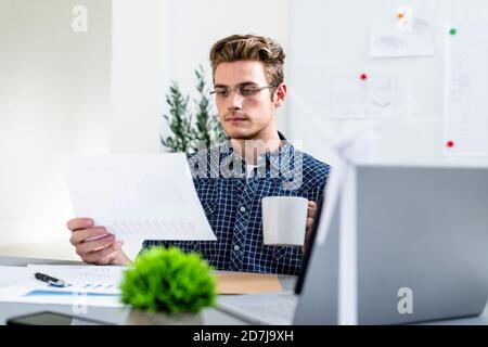 Man holding paper while drinking coffee at office Stock Photo