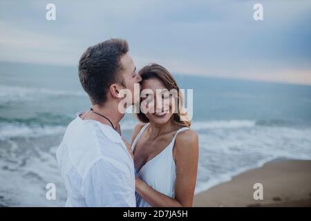 Man kissing woman while standing at beach Stock Photo