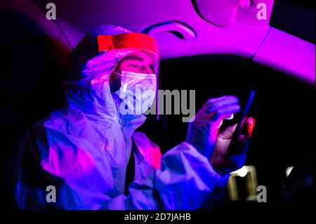 Man wearing protective suit using smart phone in ambulance at night Stock Photo