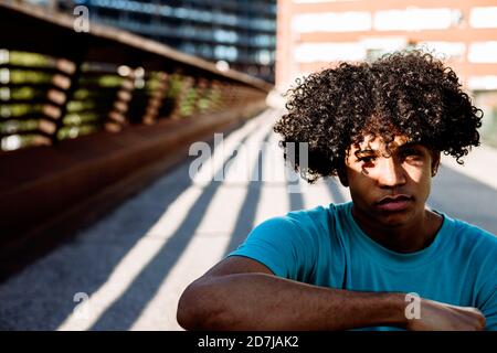 Contemplating young man sitting on street during sunny day Stock Photo