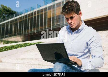 Handsome young man using laptop on sunny day Stock Photo
