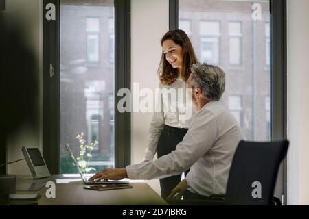 Partners using laptop while discussing at office Stock Photo