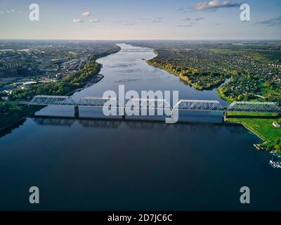 Aerial view of railway bridge over Volga River in city against sky at sunset Stock Photo