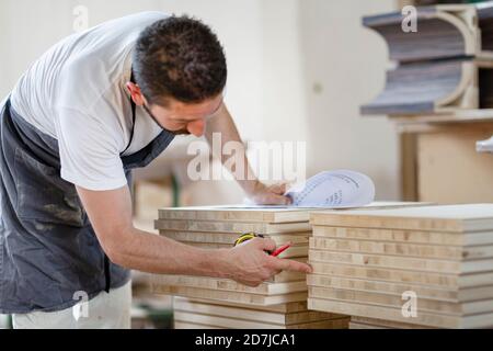 Man counting wood plank while working at workshop Stock Photo