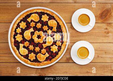 Homemade shortcrust berry pie and two white cups of coffee espresso on wooden table. Top view. Stock Photo