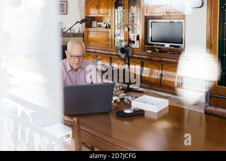 Elderly man using laptop at table Stock Photo