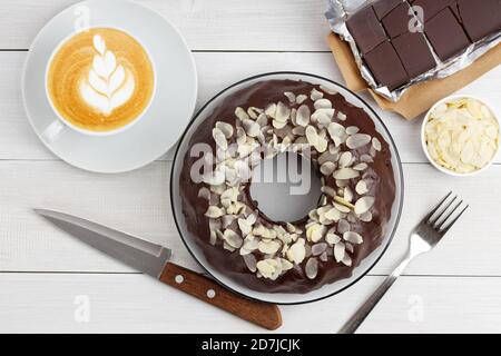 Homemade chocolate cheesecake with almond slices and cup of coffee cappuccino on white wooden table. Top view. Stock Photo