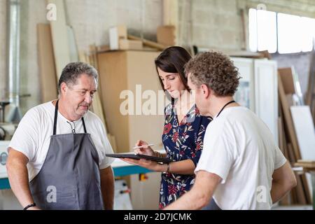 Interior designer discussing with carpenter while using digital tablet at workshop Stock Photo