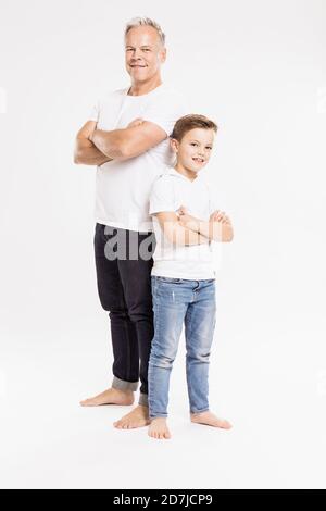 Father and son with arms crossed posing while standing against white background Stock Photo