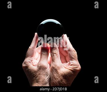 Senior caucasian hands holding a crystal futures or fortune telling ball with black center to allow compositing of your logo Stock Photo