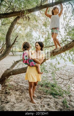 Mother and daughters standing near willow tree Stock Photo