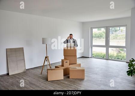 Mature man using laptop while standing in new house Stock Photo